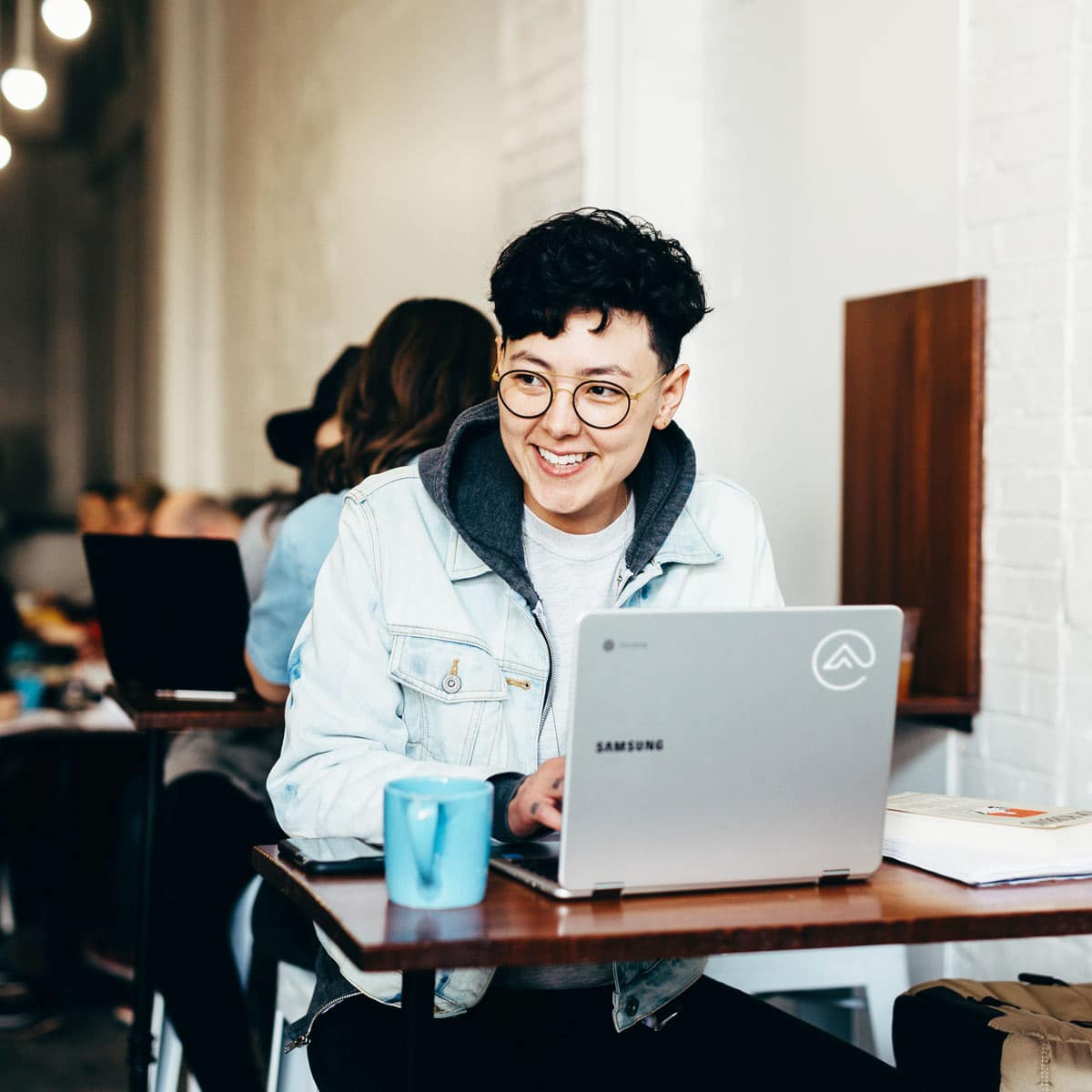 Young man smiling while on a laptop in a coffee shop